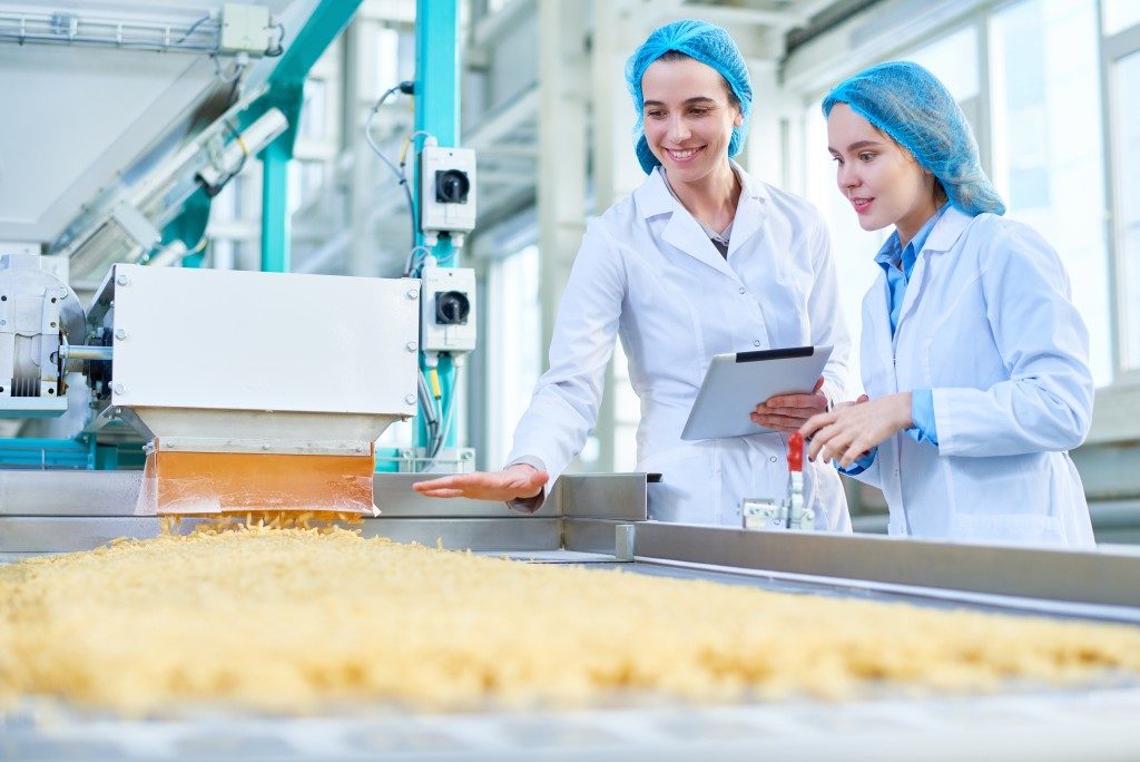 two women wearing lab coats inside a factory