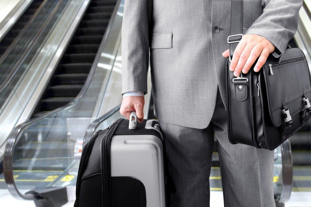Businessman with his luggage near an escalator at an airport