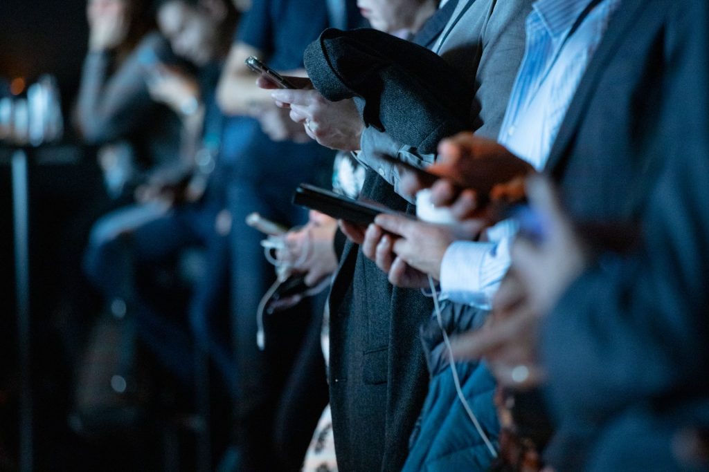 people facing forward in a line using their mobile phones
