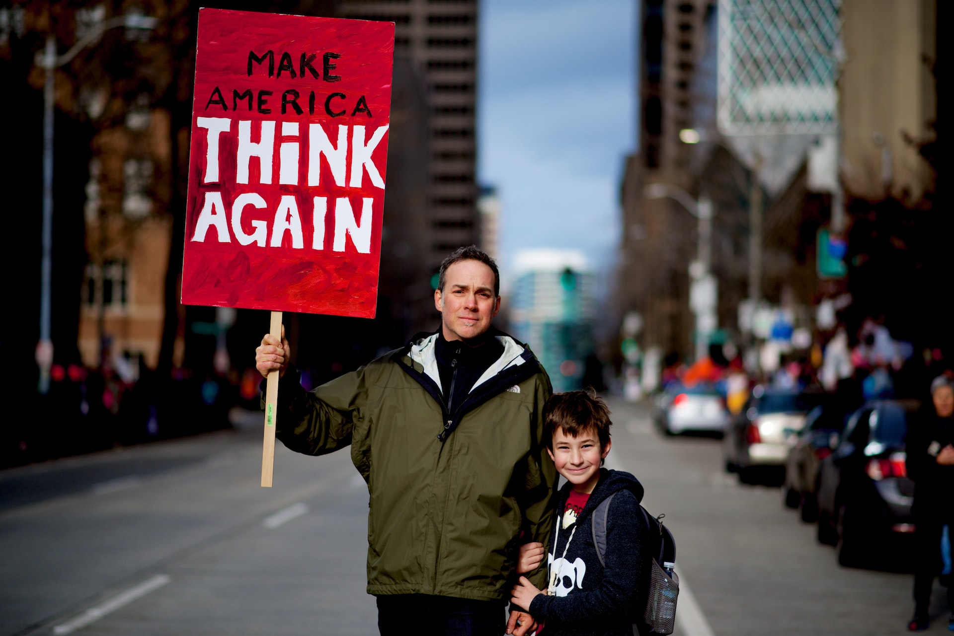 man holding protest sign with boy in street