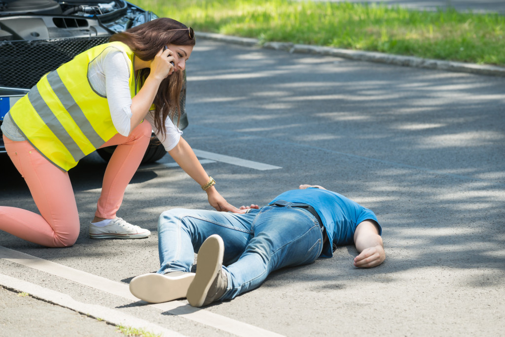 A man lying on the road after a car accident