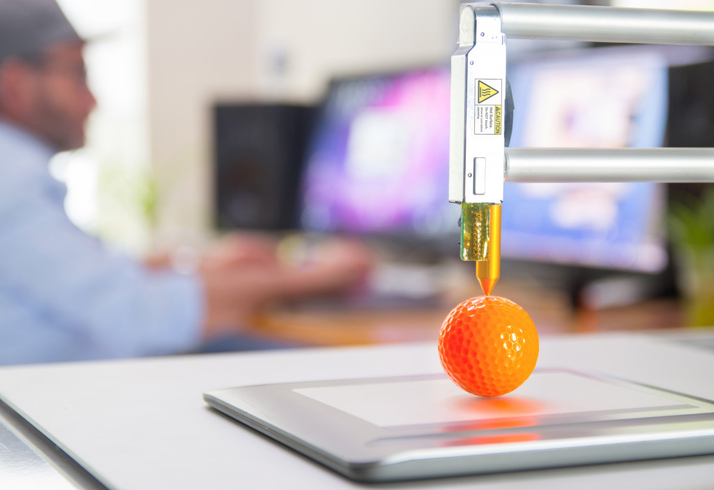 Golf ball printed using a 3d printer with a man in the background.