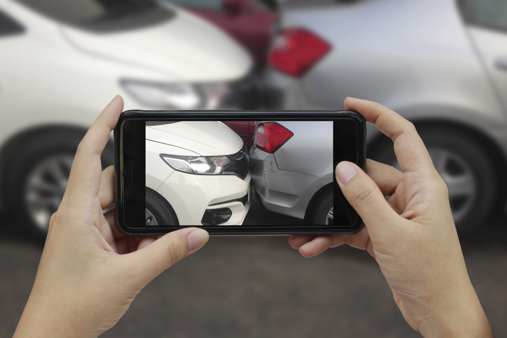 A person taking a photo of the car damage after a collision